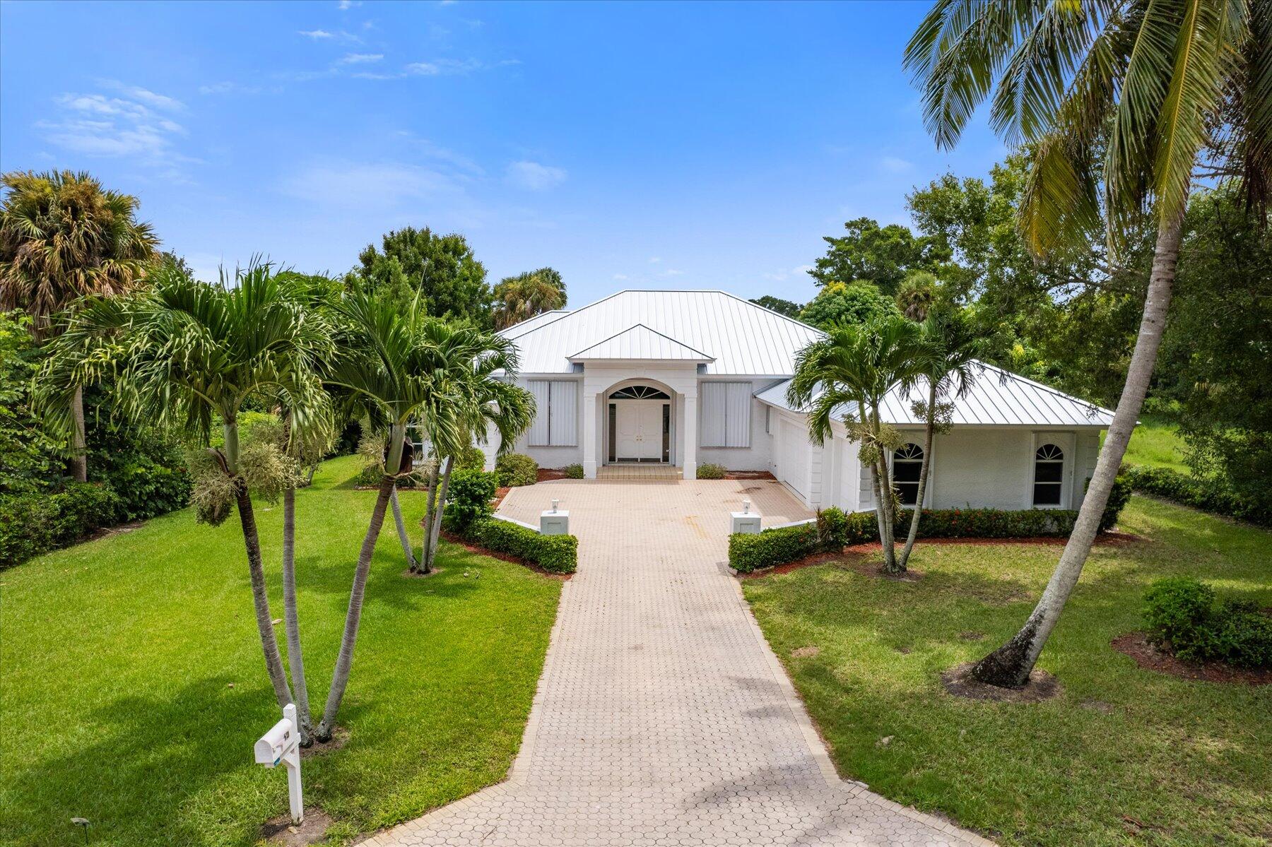 a front view of a house with garden and trees