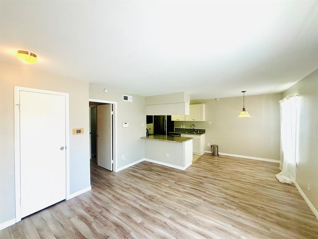 a view of kitchen and empty room with wooden floor