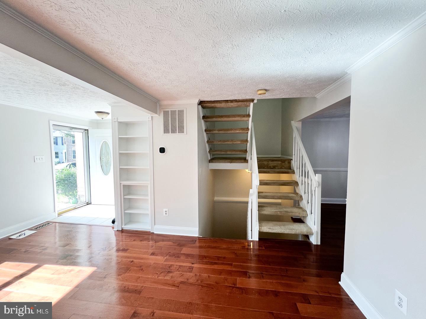 an entryway of a house with wooden floor and stairs