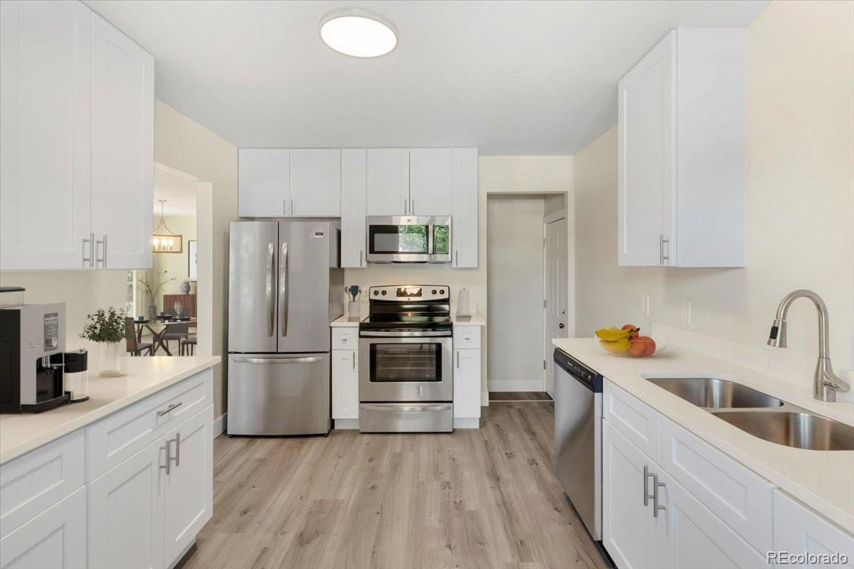 a kitchen with stainless steel appliances a refrigerator stove and sink with wooden floor