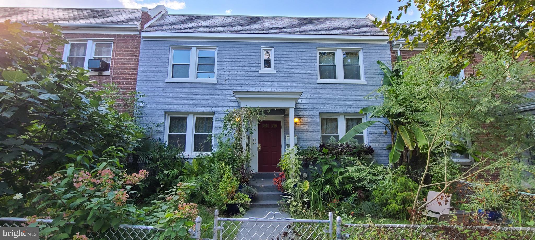 front view of a brick house with large windows and a small yard