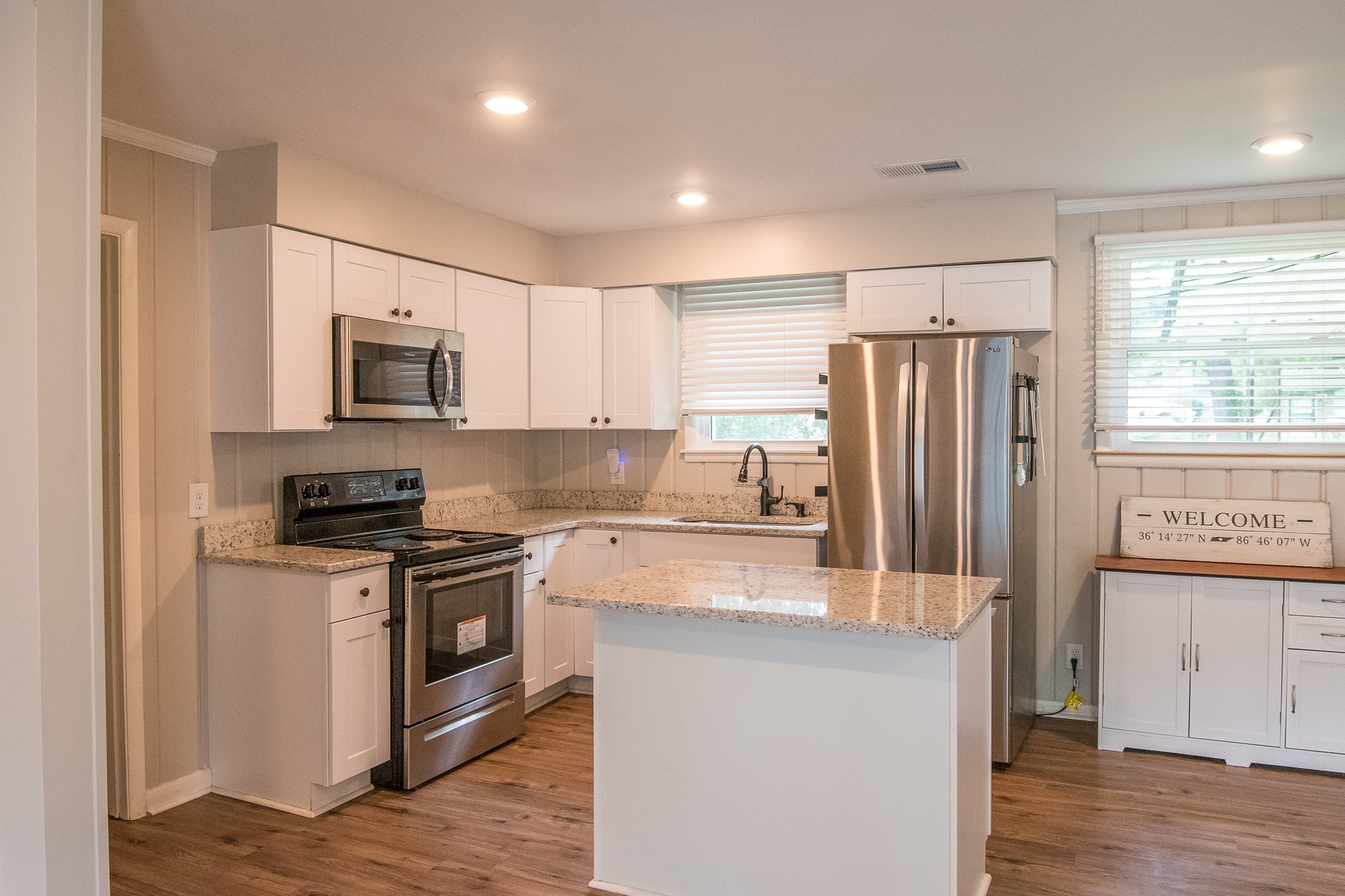 a kitchen with kitchen island granite countertop a refrigerator stove top oven and sink