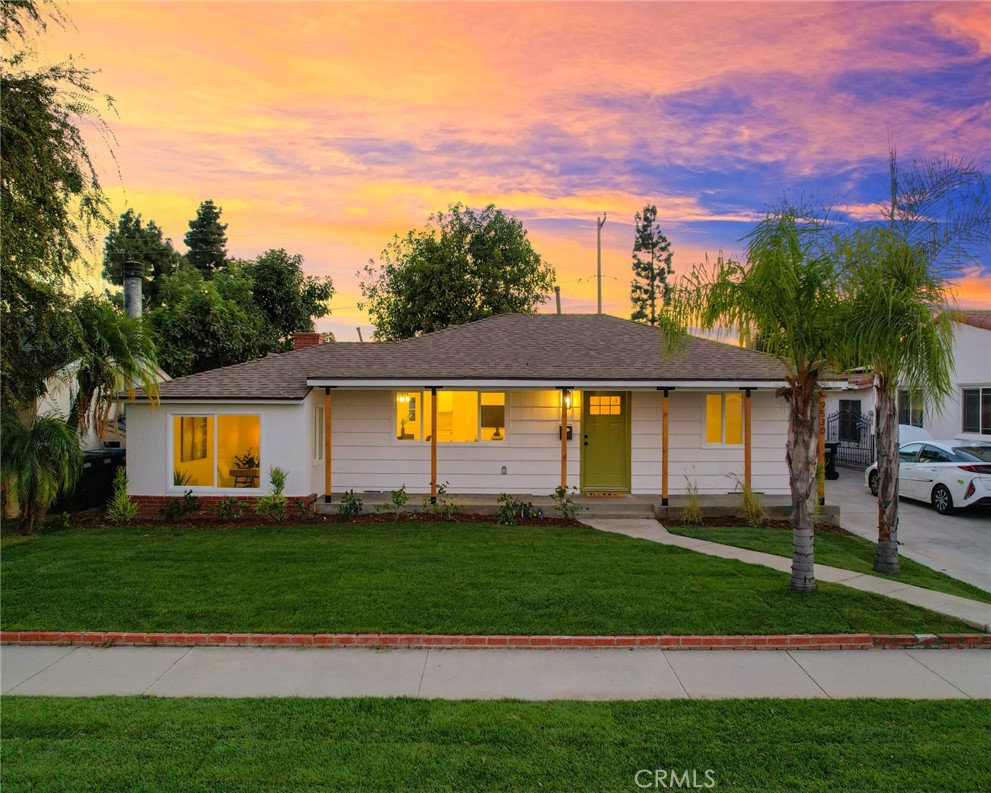 a front view of a house with a yard and trees