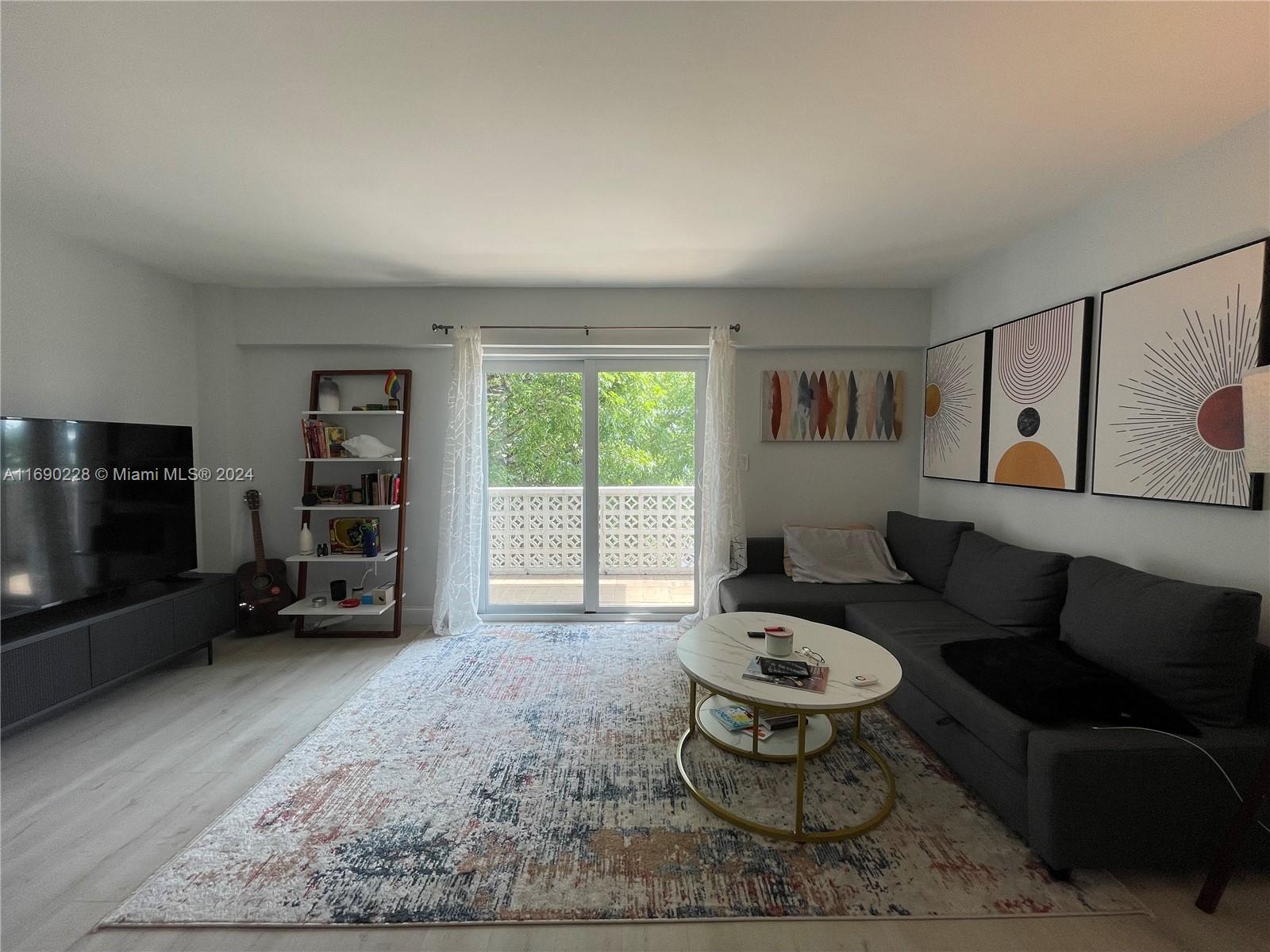 a living room with furniture a window and a flat screen tv