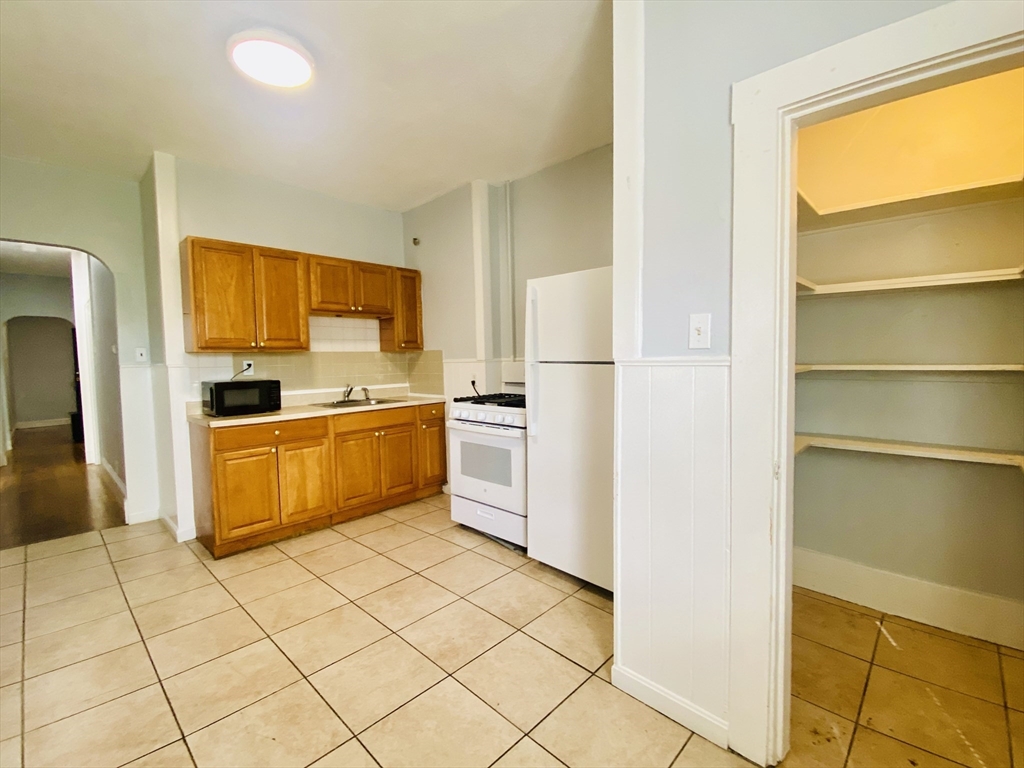 a kitchen with a stove a sink and a refrigerator with wooden floor