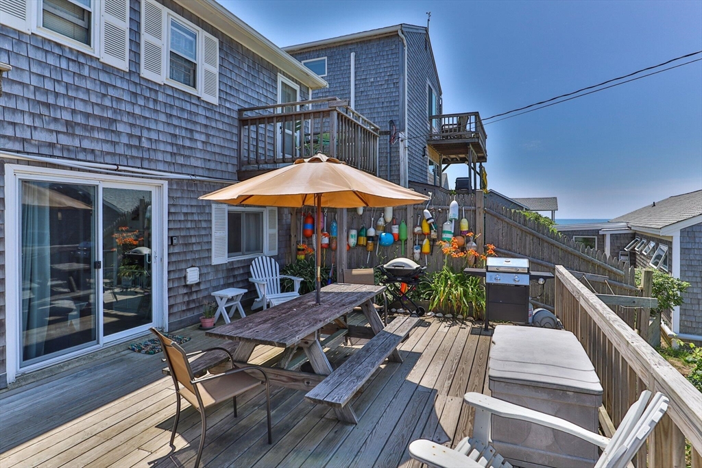 a view of house with wooden deck and outdoor seating