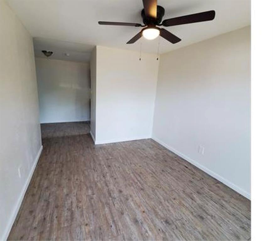 an empty room with wooden floor ceiling fan and windows