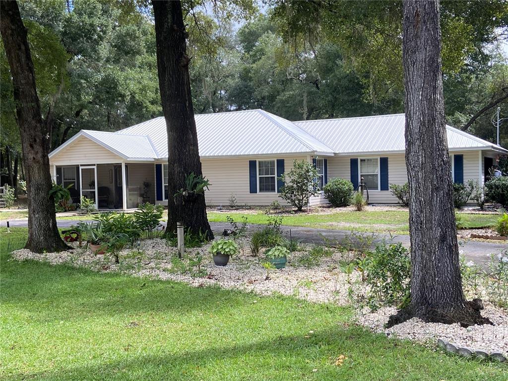 a front view of a house with a yard and large tree