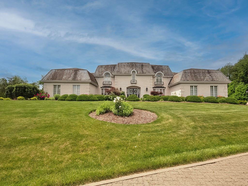 a view of a big house with a big yard and large trees