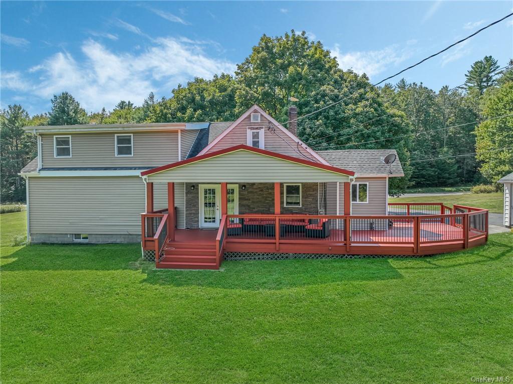 Rear view of house with a deck and a yard