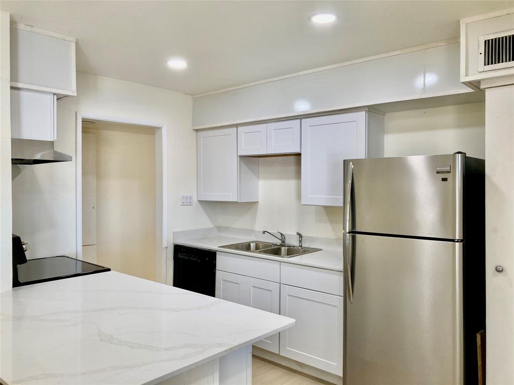 a kitchen with a refrigerator a stove top oven a sink and cabinets