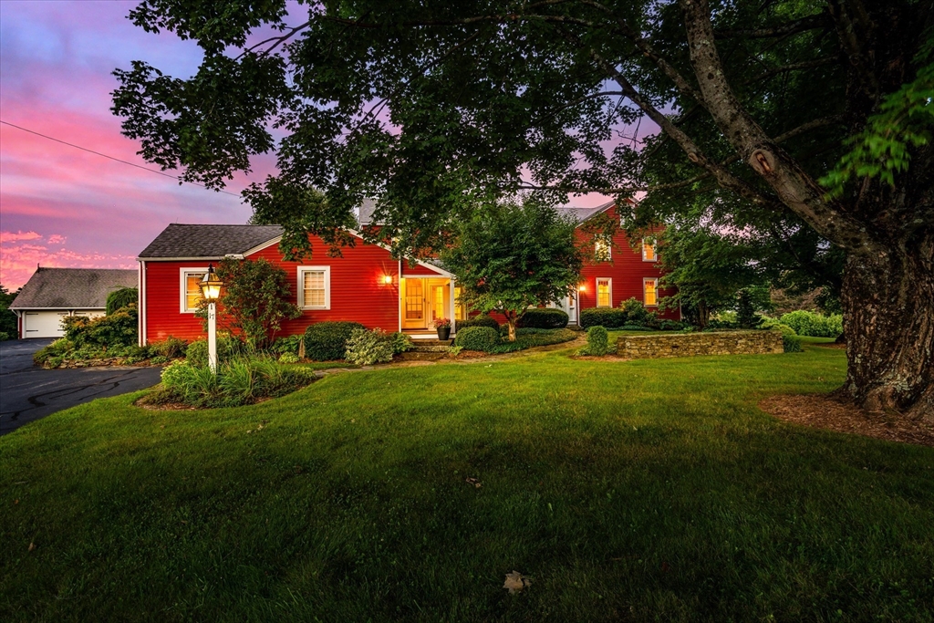 a front view of a house with a garden and trees