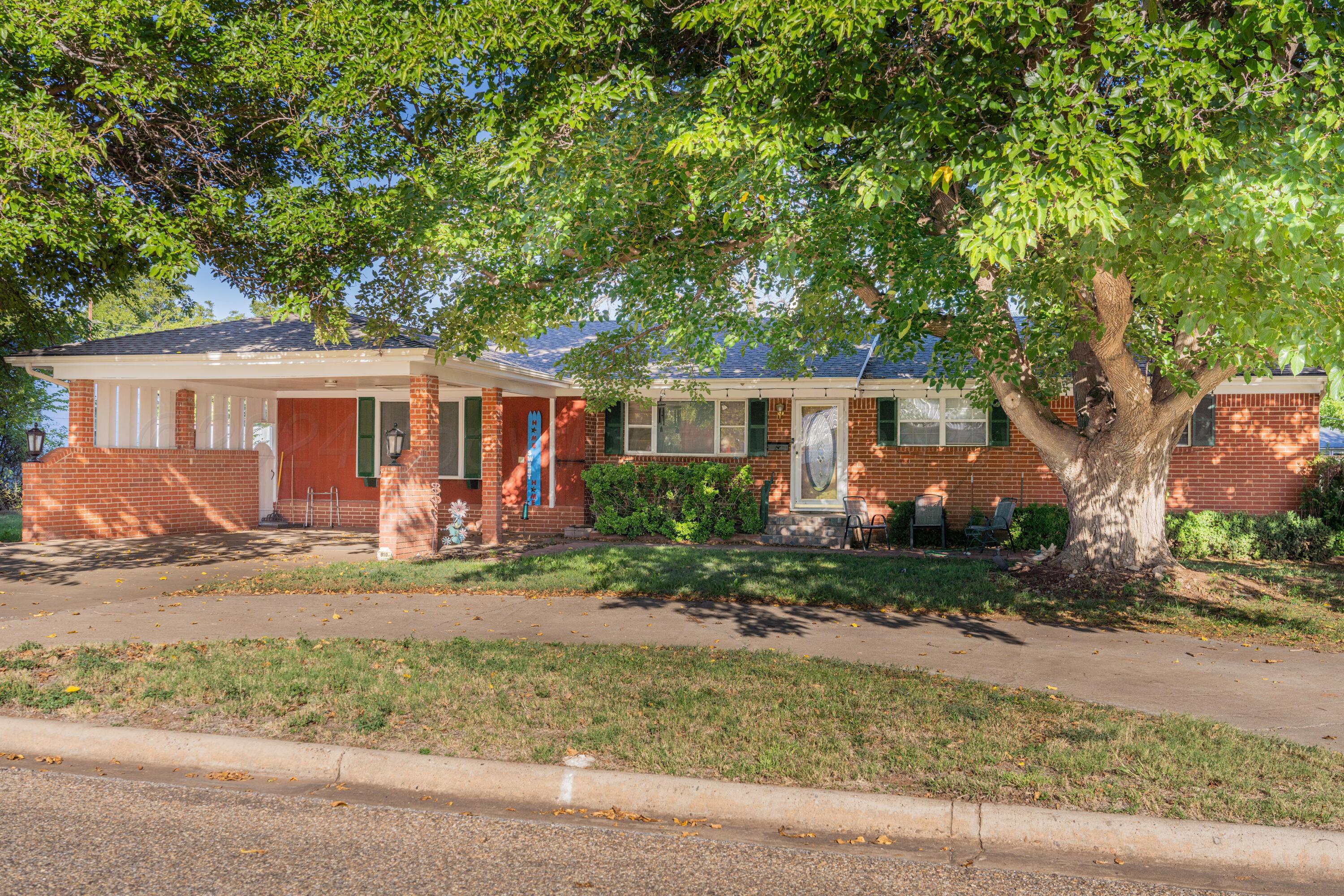 front view of a house with potted plants and large trees