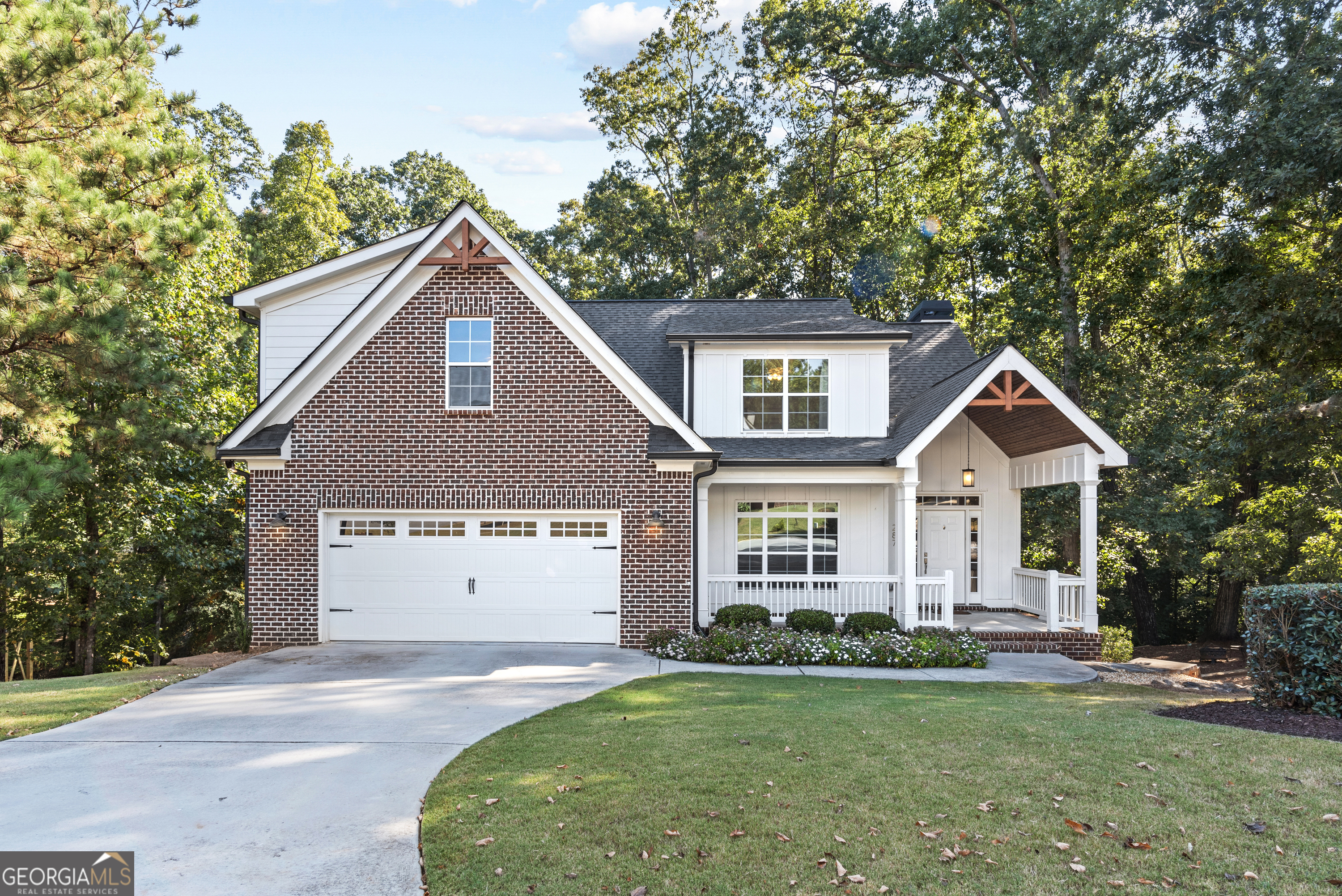 a front view of a house with a garden and trees