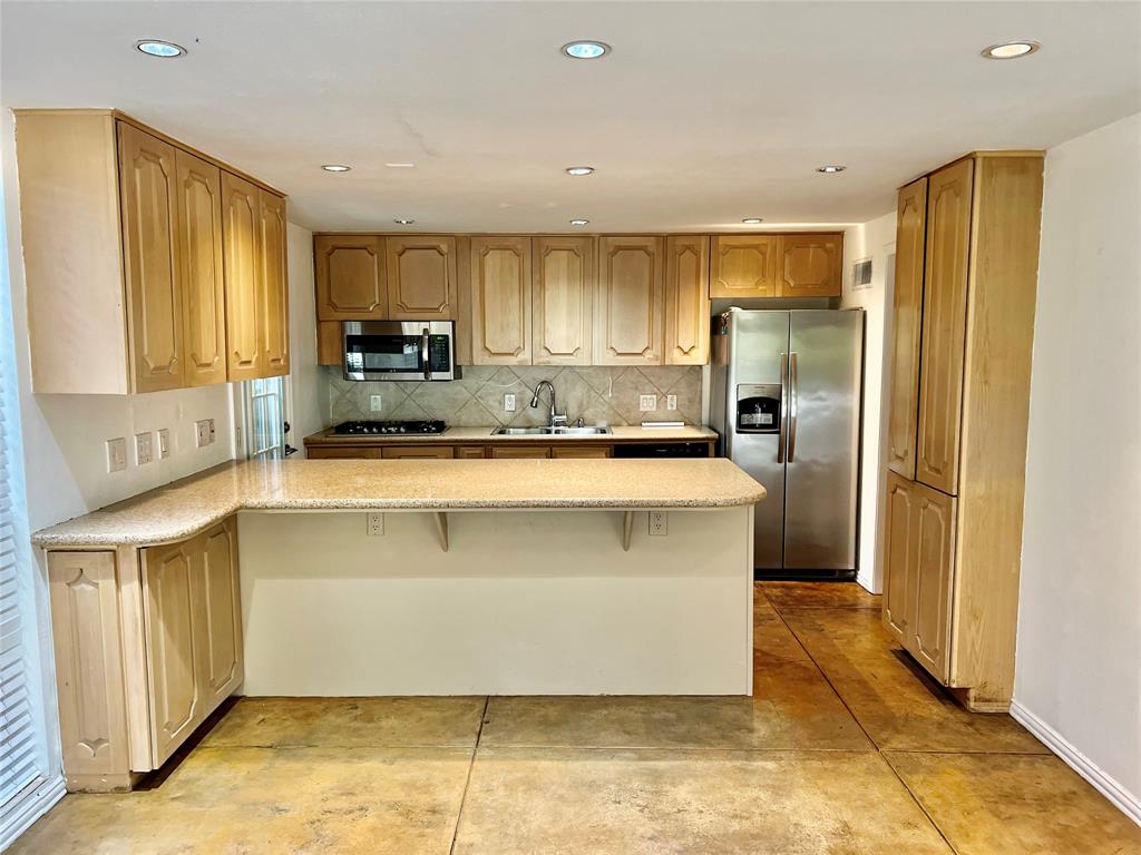 a kitchen with stainless steel appliances granite countertop a refrigerator a stove and a sink