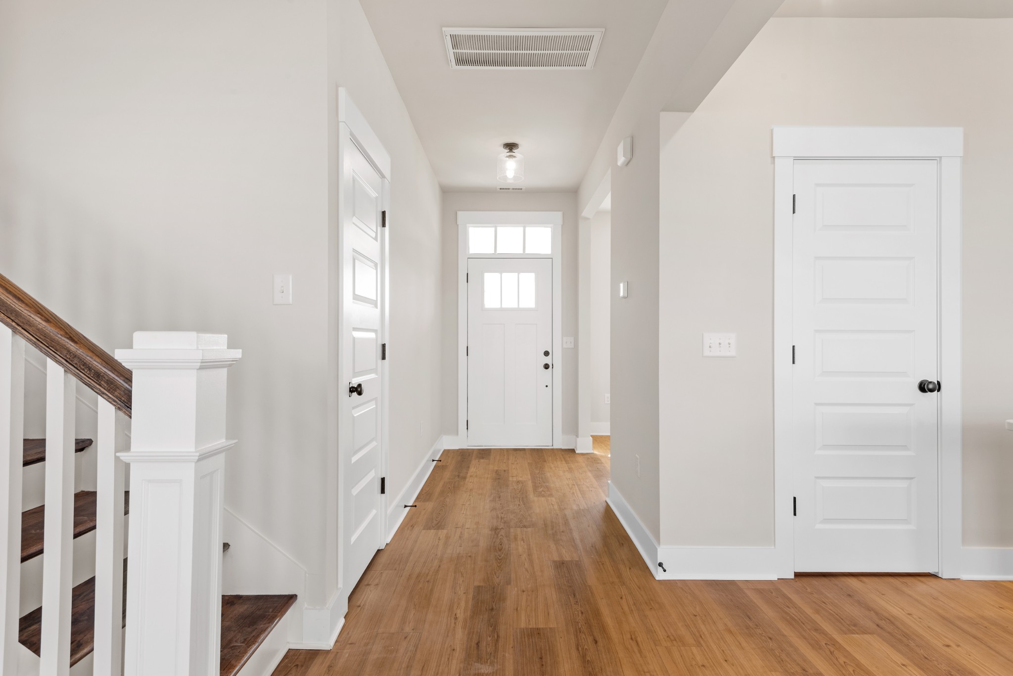 a view of a hallway with wooden floor and a bathroom