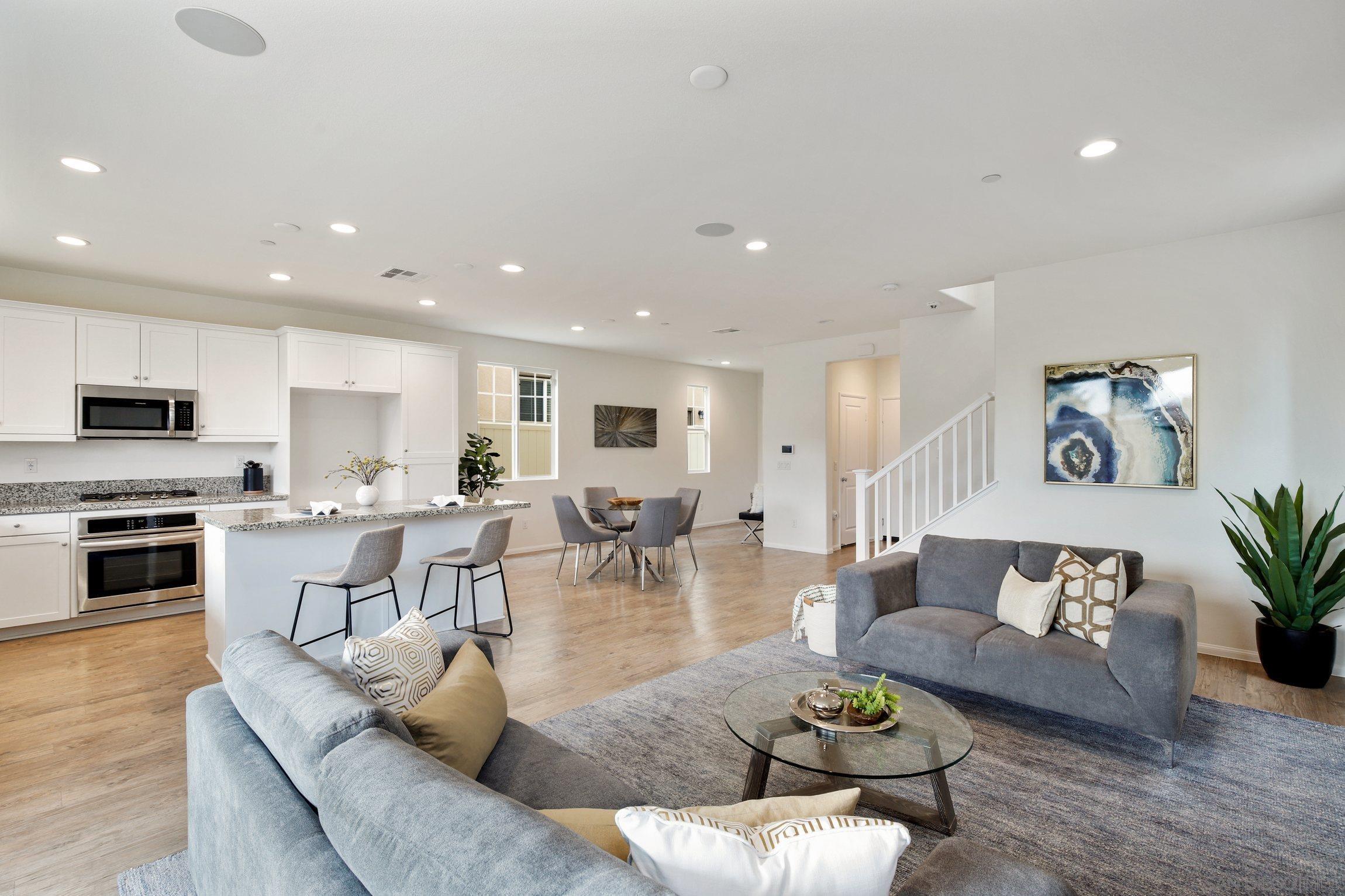 a living room with furniture wooden floor and kitchen view