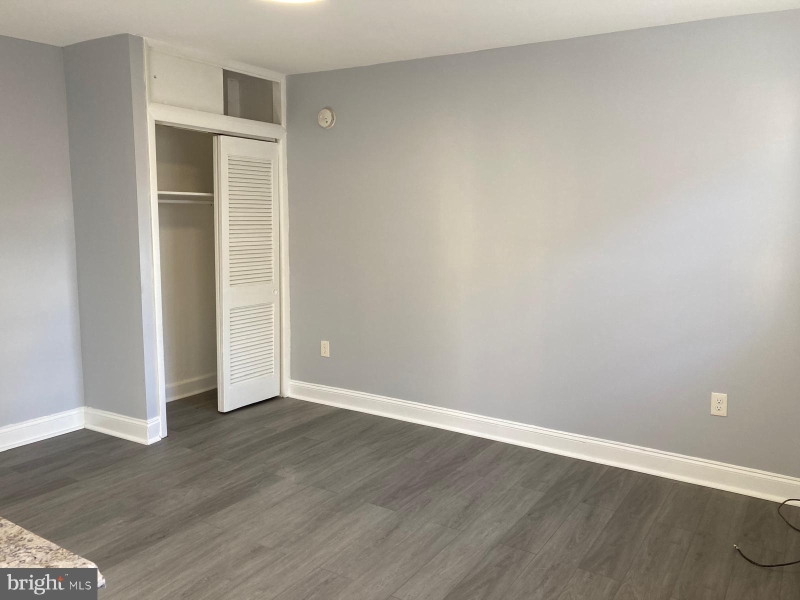 a view of an empty room with wooden floor and closet