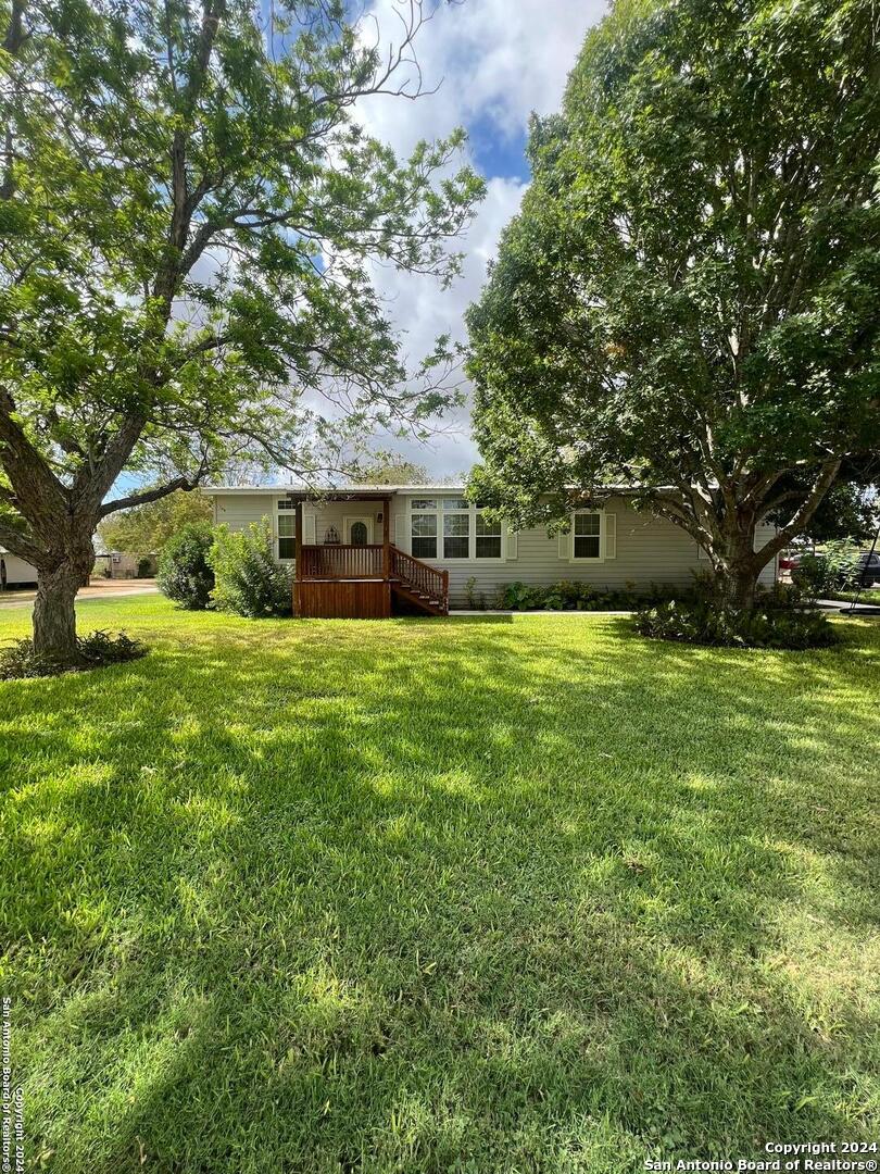 a view of a house with a big yard and large trees