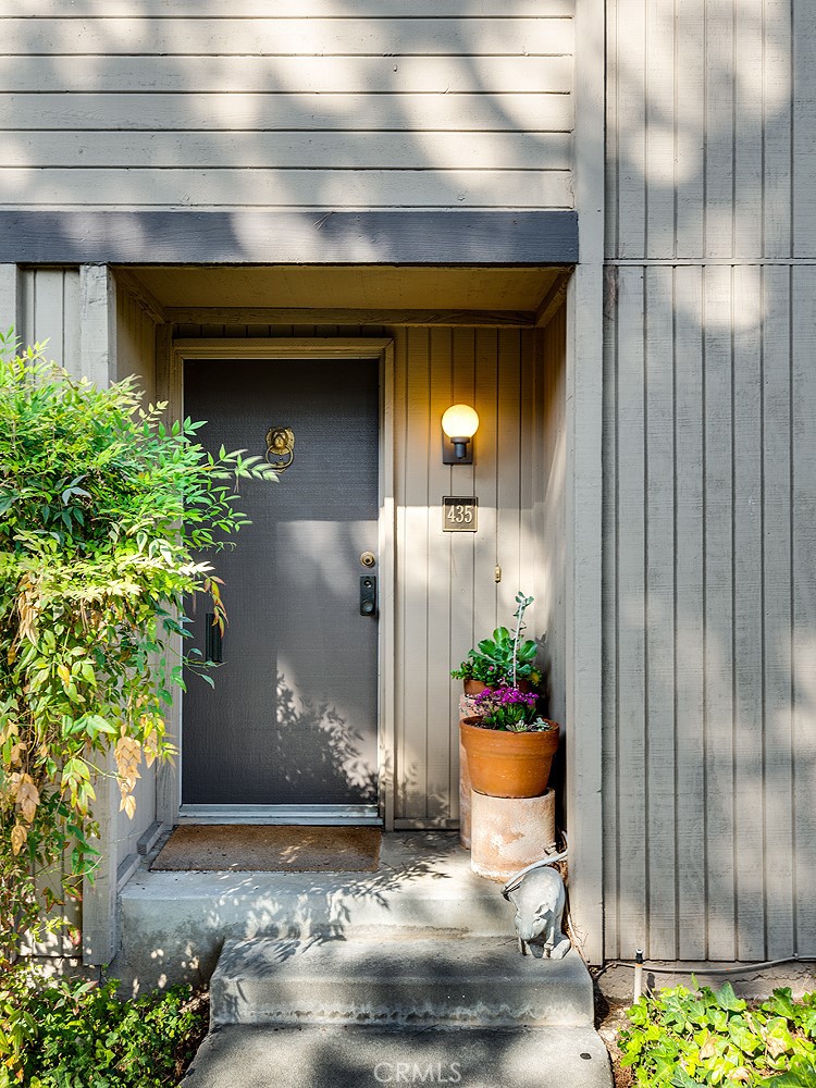 a view of a house with potted plants and a bench