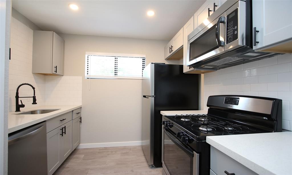 a kitchen with stainless steel appliances a sink stove and cabinets