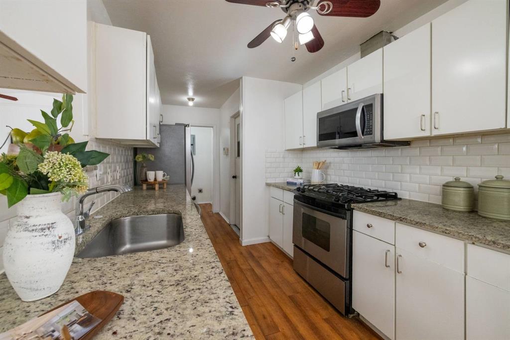 a kitchen with granite countertop a sink stainless steel appliances and cabinets