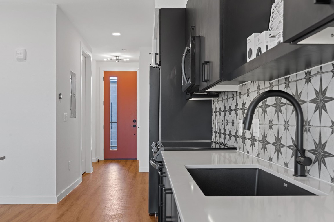 a kitchen with a sink a refrigerator and wooden floor