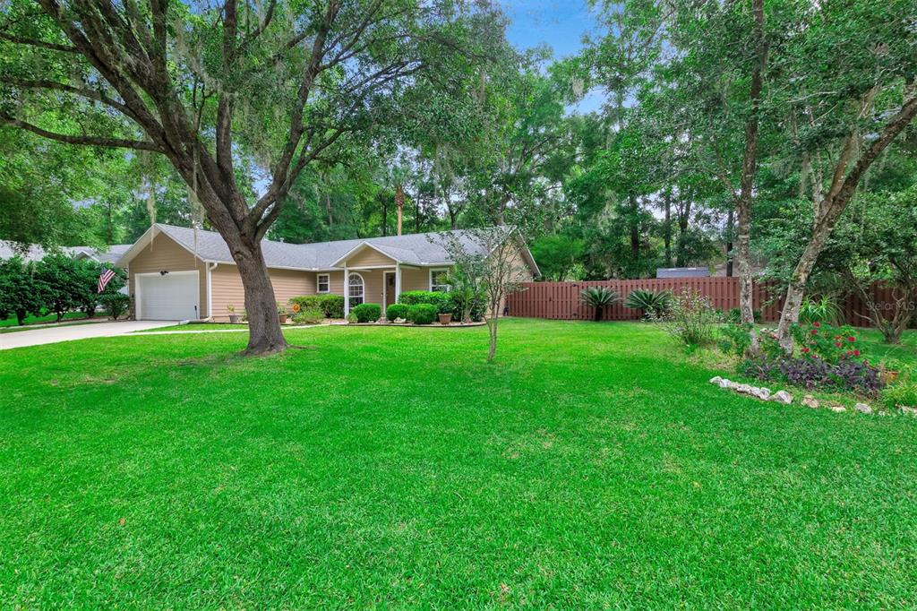 a front view of a house with garden and tree