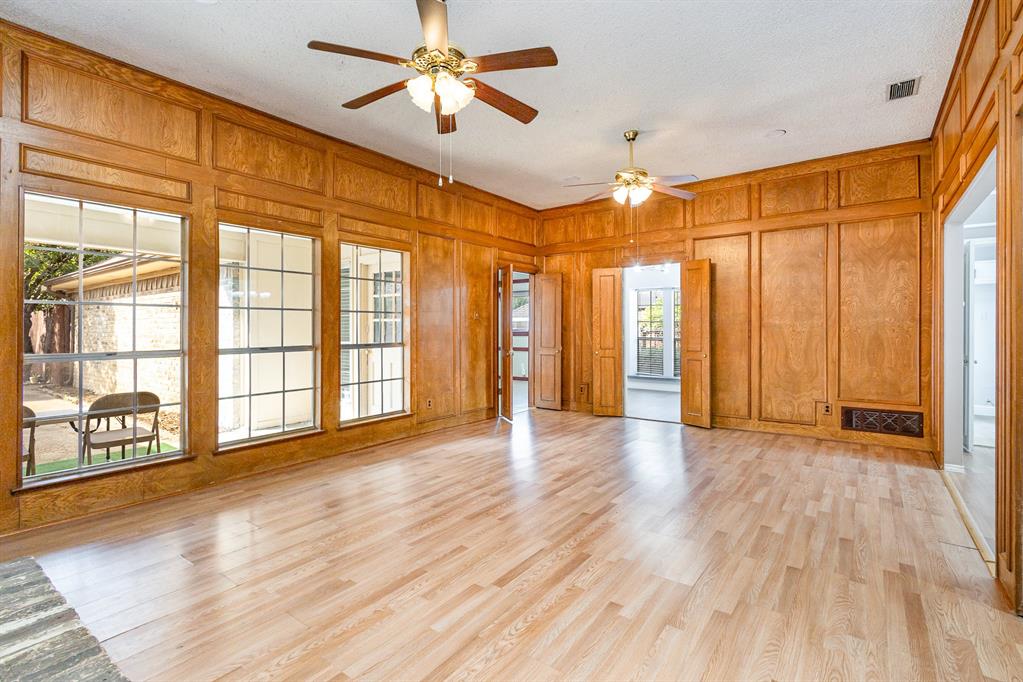 a view of an empty room with a window and wooden floor