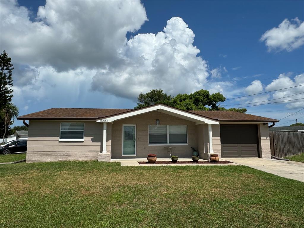 a front view of house with yard and trees in the background