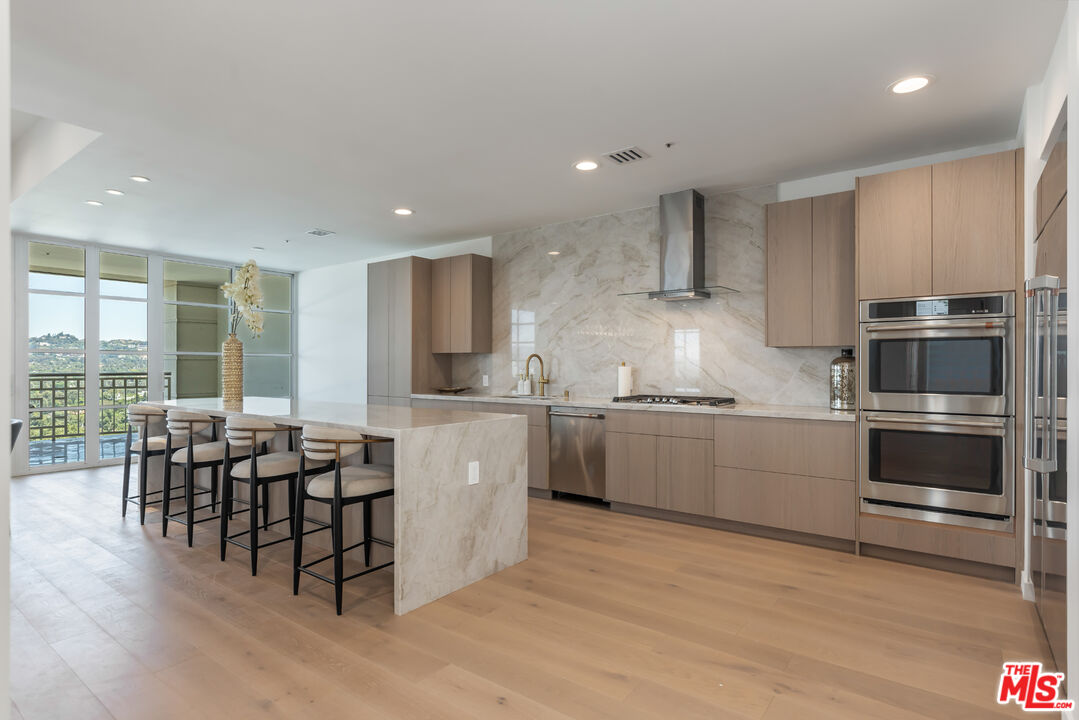 a kitchen with stainless steel appliances kitchen island granite countertop a table chairs sink and cabinets