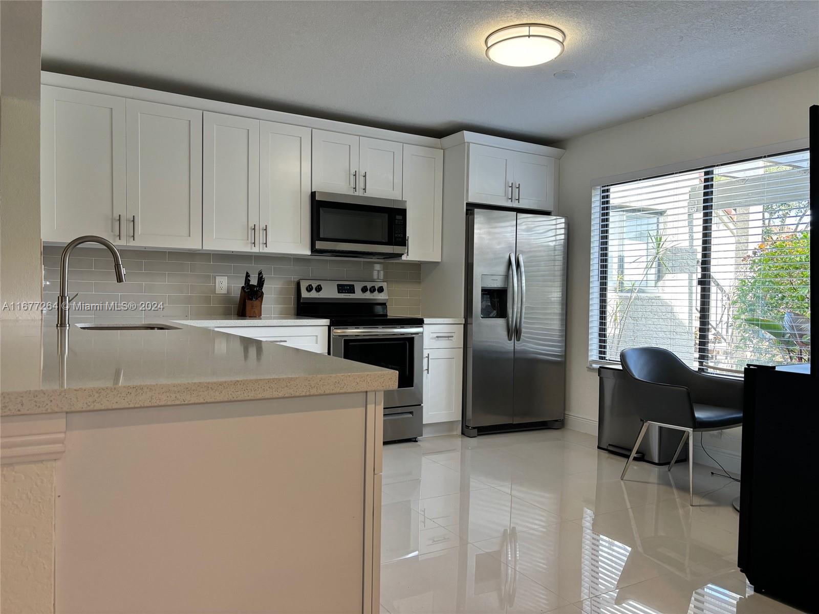 a kitchen with a sink a stove a refrigerator cabinets and a dining table