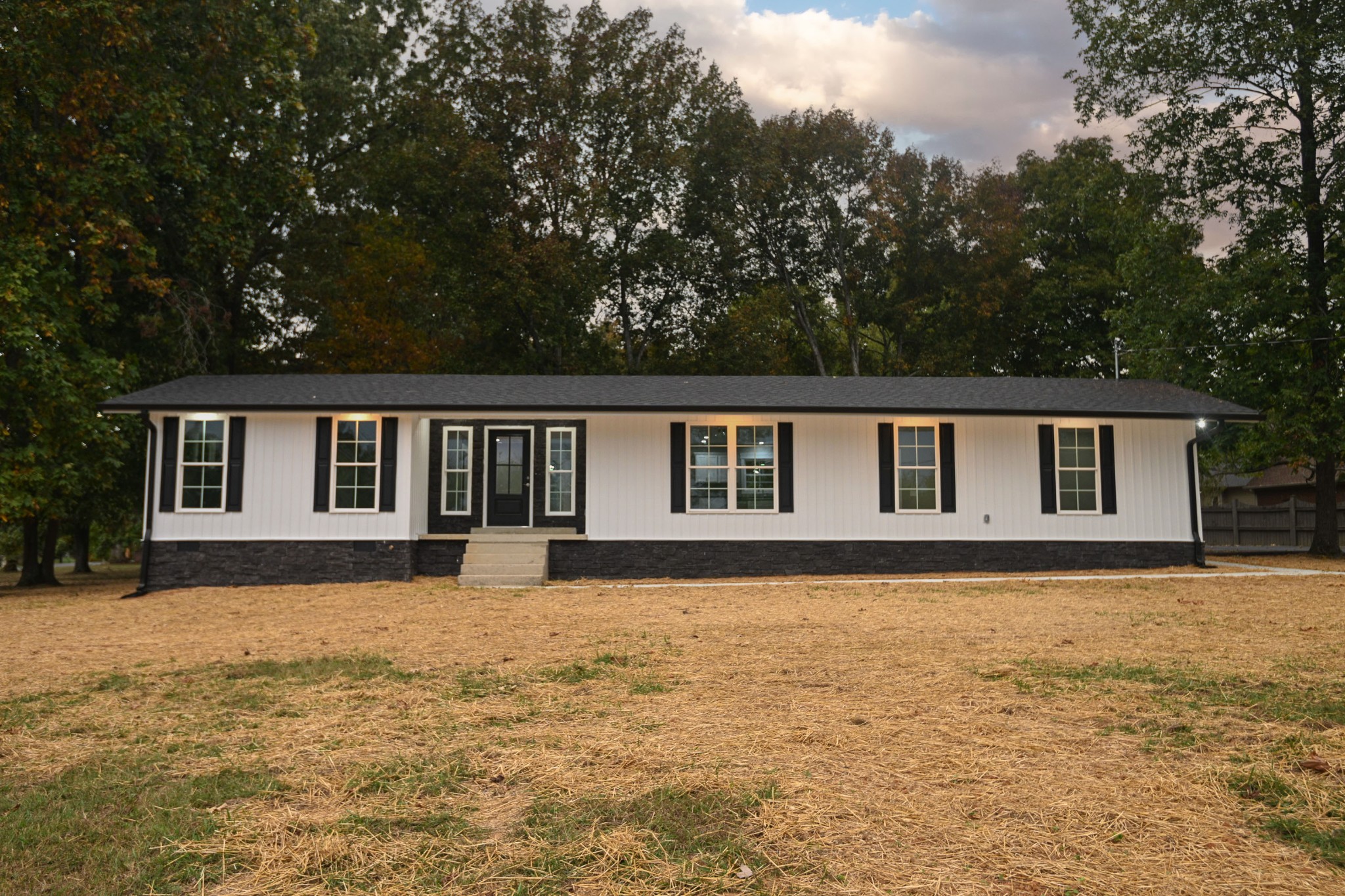 a front view of house with yard and trees all around