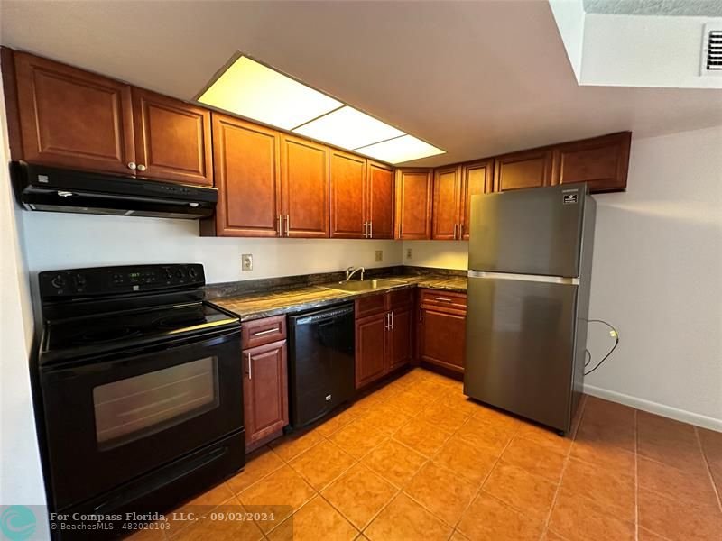 a kitchen with stainless steel appliances granite countertop a stove a refrigerator and a sink with wooden floor