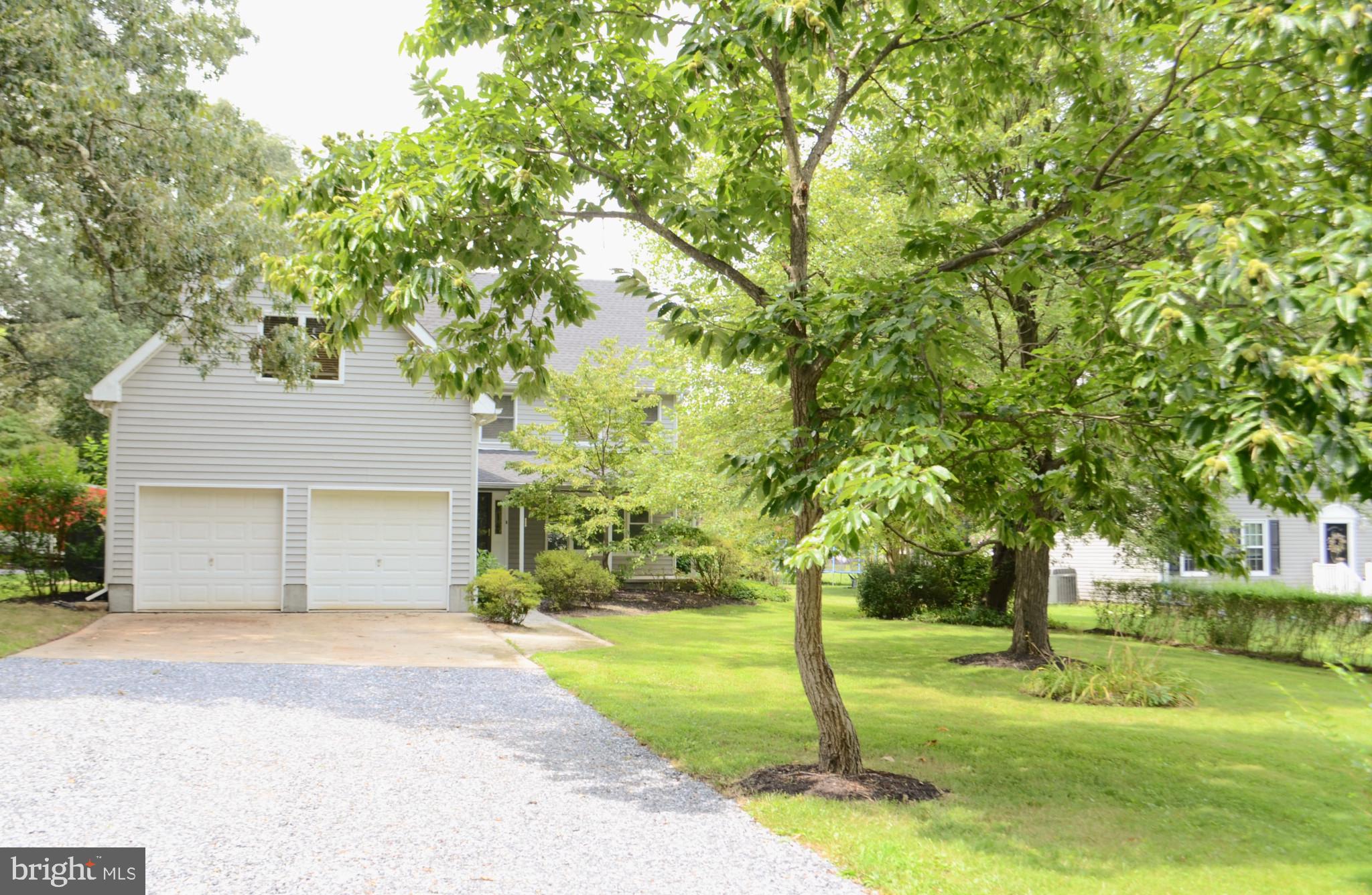 a front view of a house with a yard and tree s