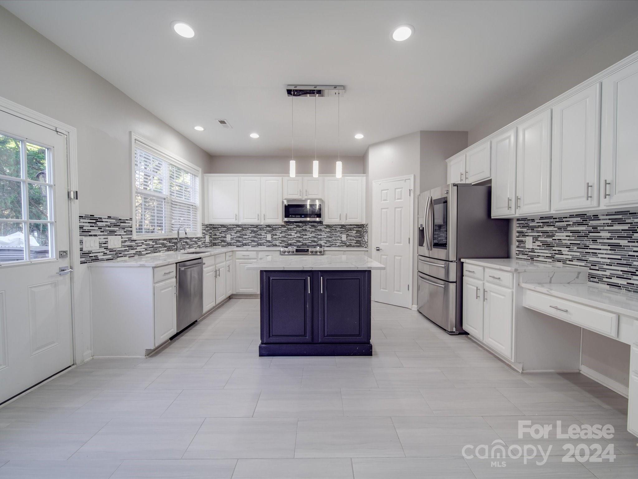 a kitchen with stainless steel appliances kitchen island granite countertop a stove sink and refrigerator