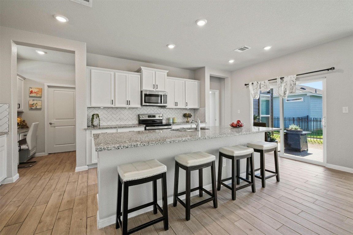 a kitchen with stainless steel appliances granite countertop a white cabinets and wooden floor