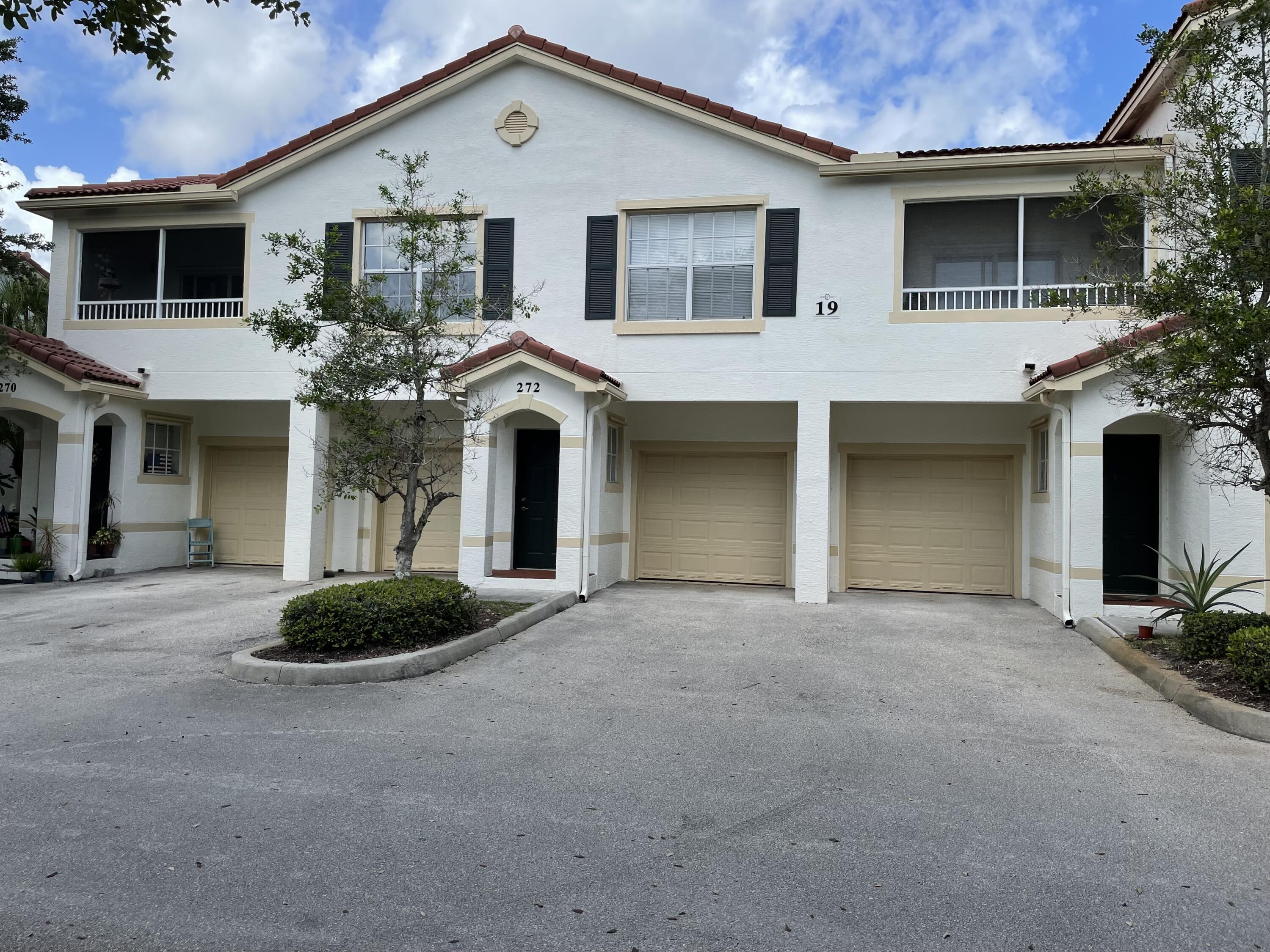 a front view of a house with plants and garage