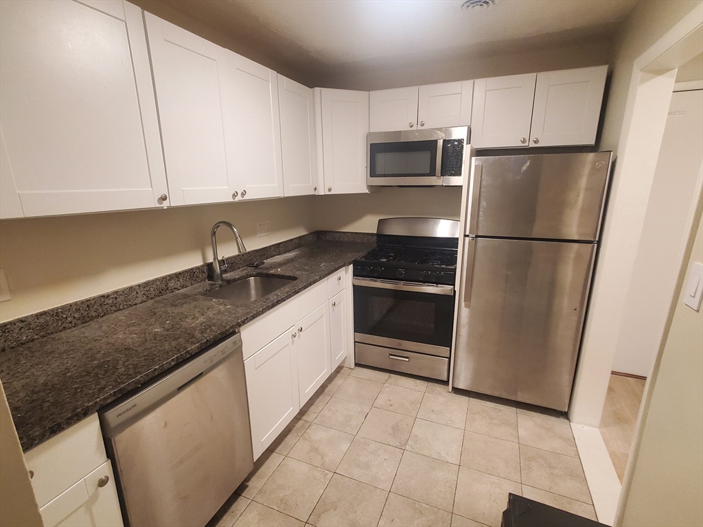 a kitchen with granite countertop a refrigerator sink and cabinets