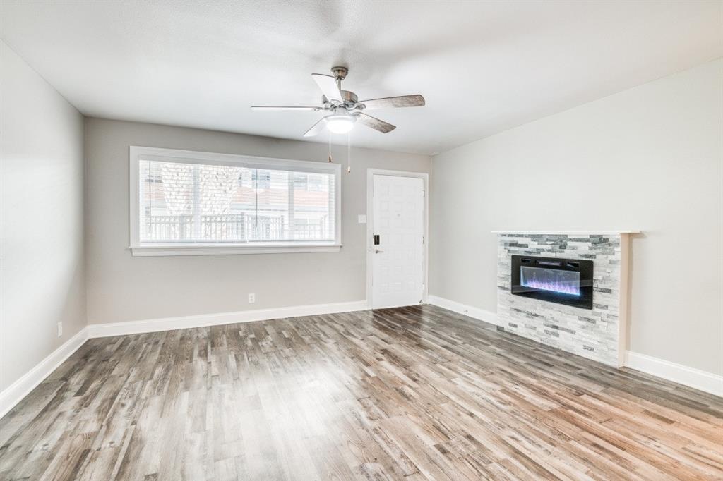 an empty room with wooden floor chandelier fan and windows