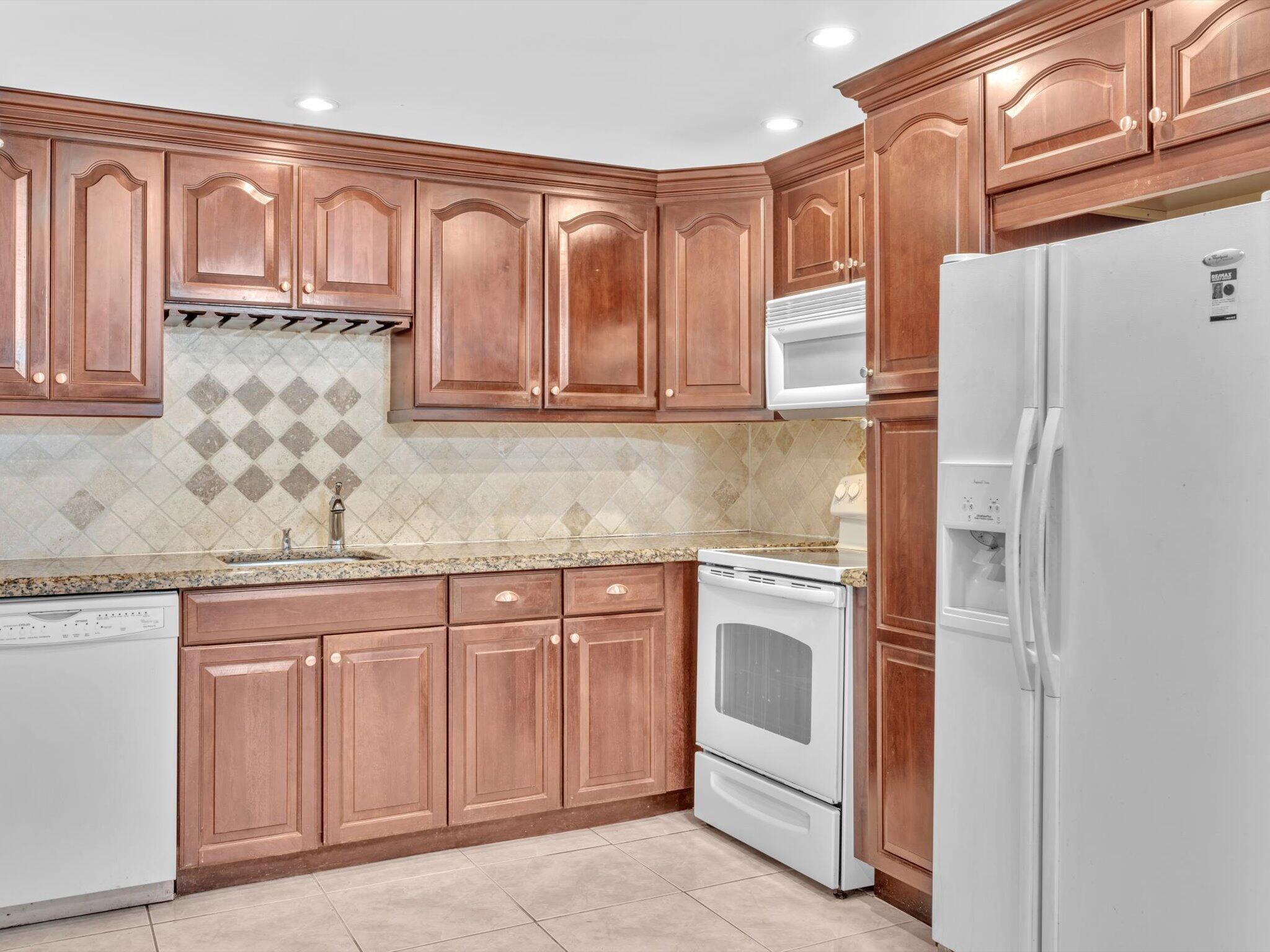 a kitchen with granite countertop white cabinets and stainless steel appliances