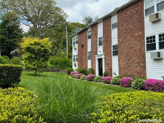 a front view of house and yard with beautiful flowers and green space