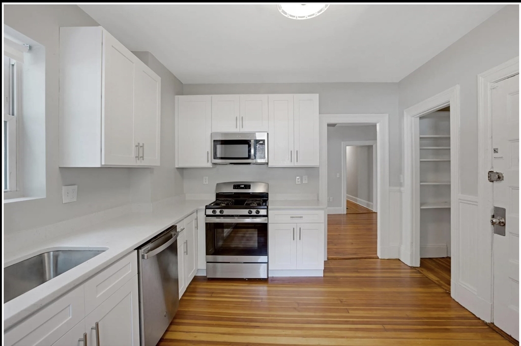 a kitchen with granite countertop a stove top oven and cabinets