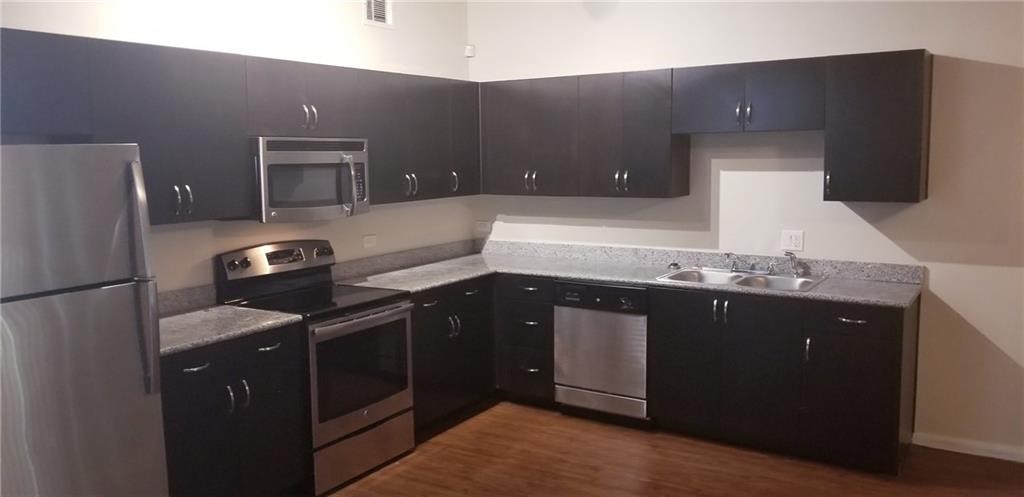 a kitchen with stainless steel appliances granite countertop a refrigerator and a stove