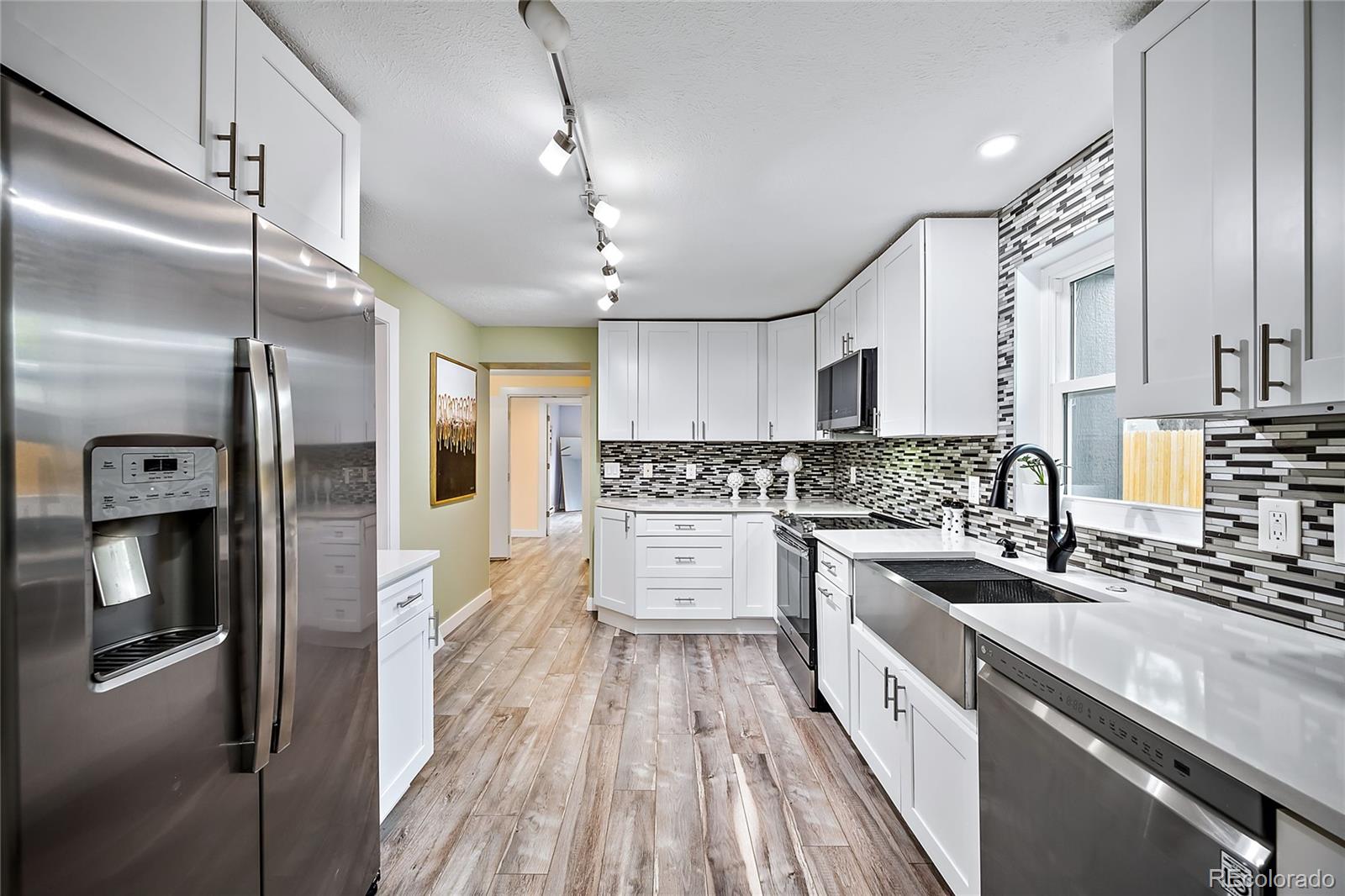 a large kitchen with a lot of counter space a sink and stainless steel appliances