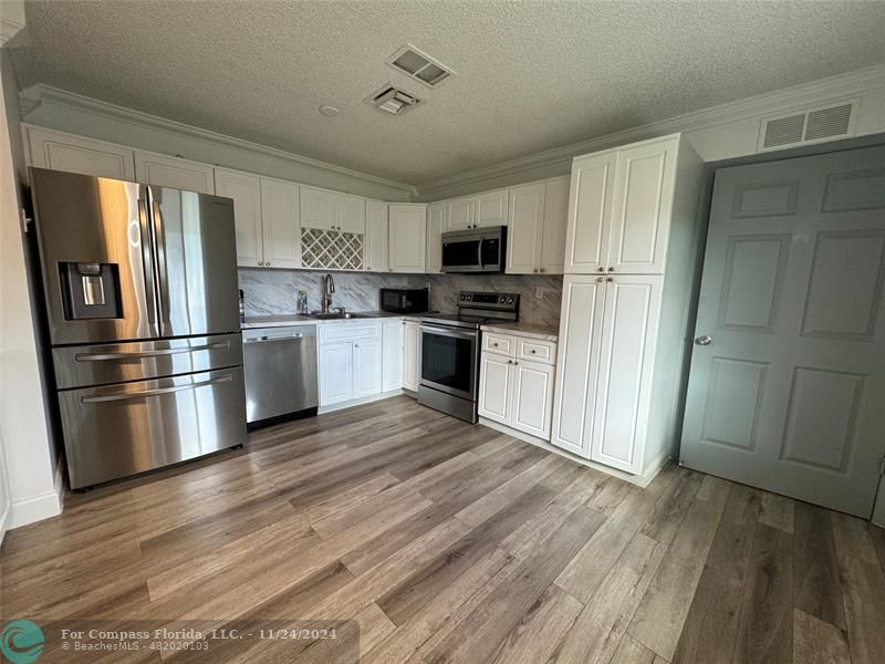 a kitchen with stainless steel appliances wooden floor and sink