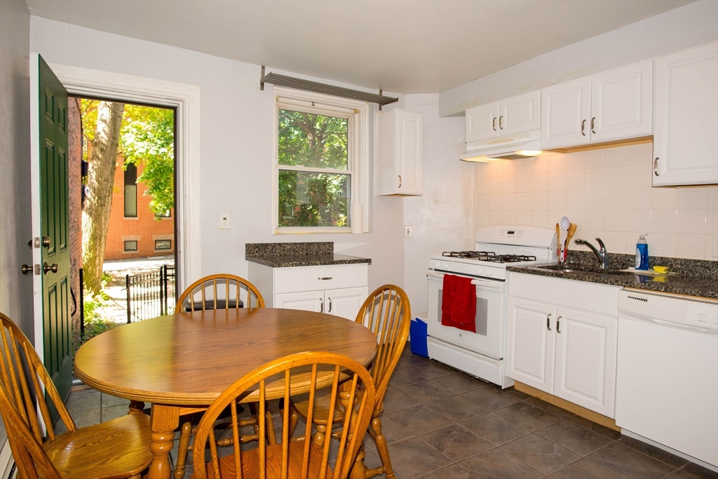 a kitchen with granite countertop a stove a sink a dining table and chairs