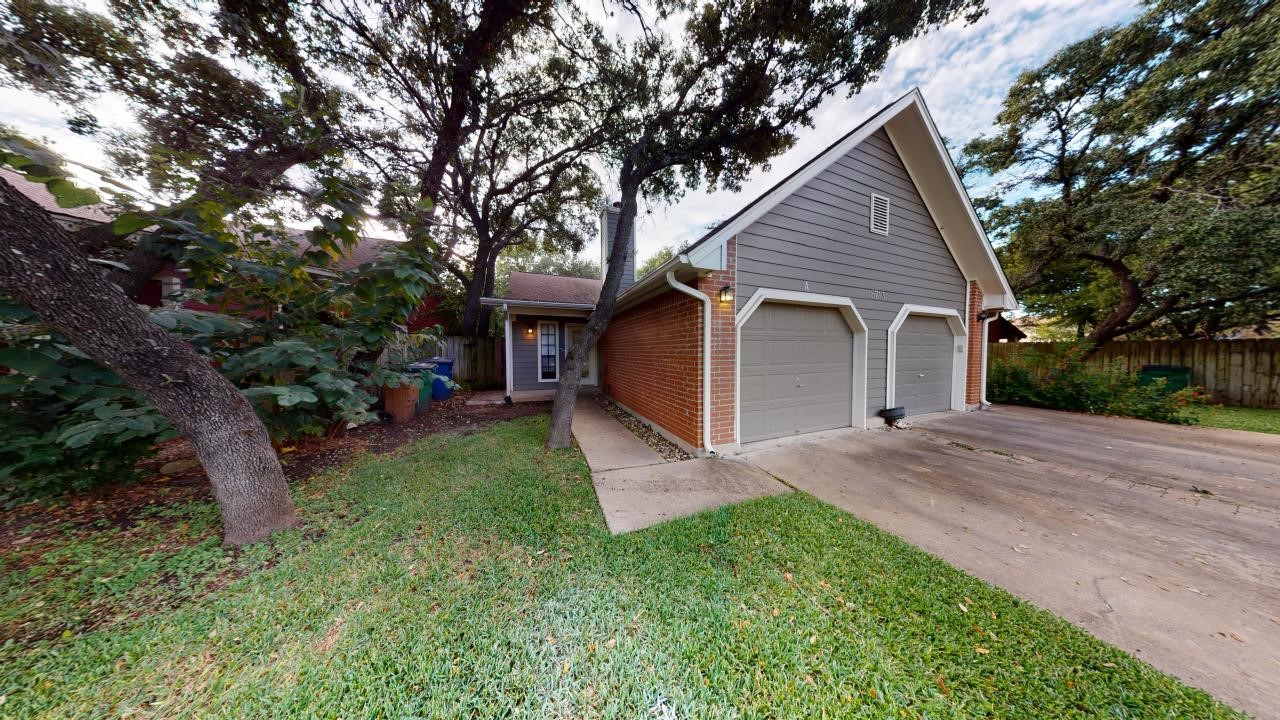 a view of a house with a yard plants and large tree