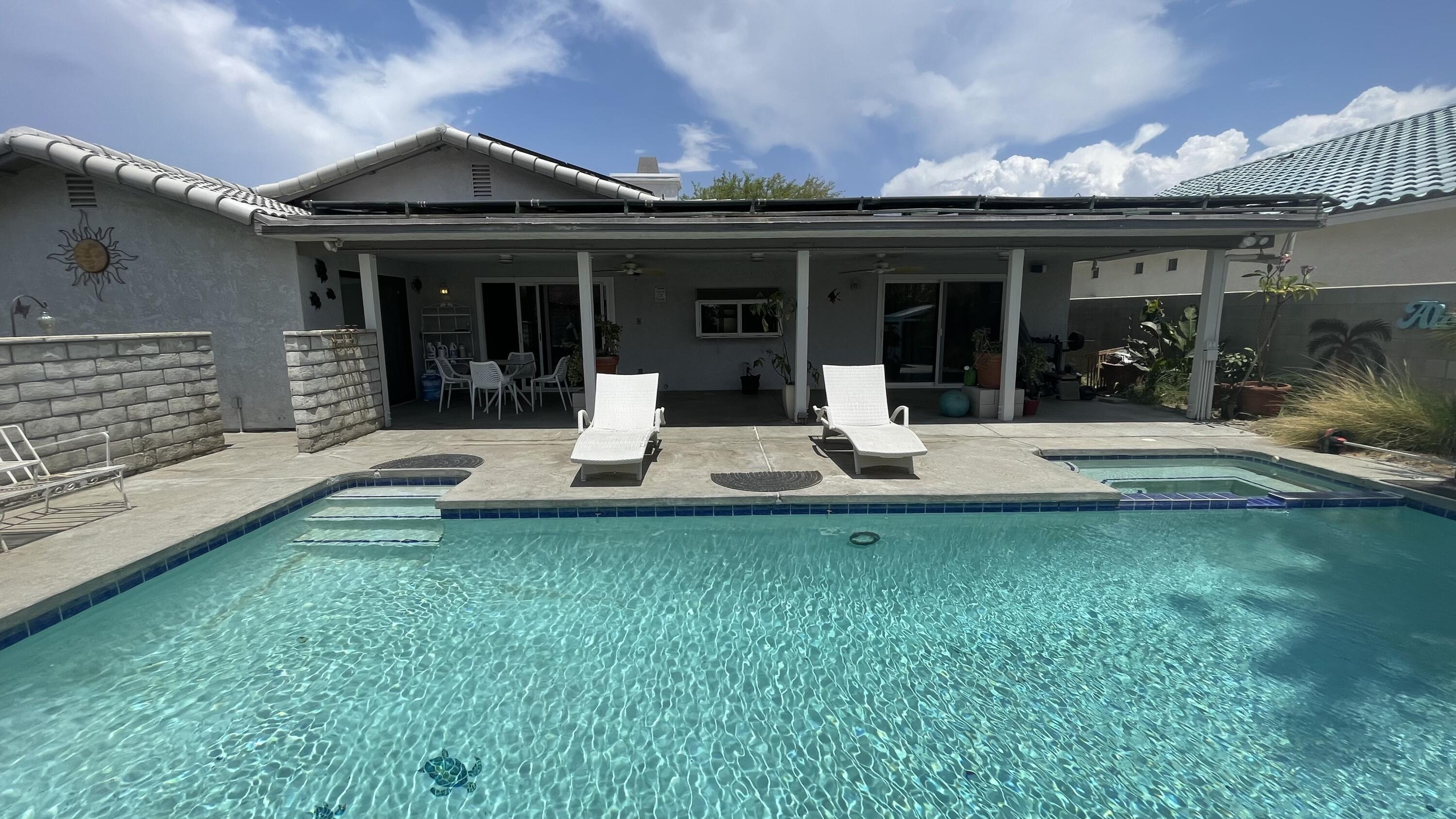 a front view of a house with swimming pool and porch with furniture