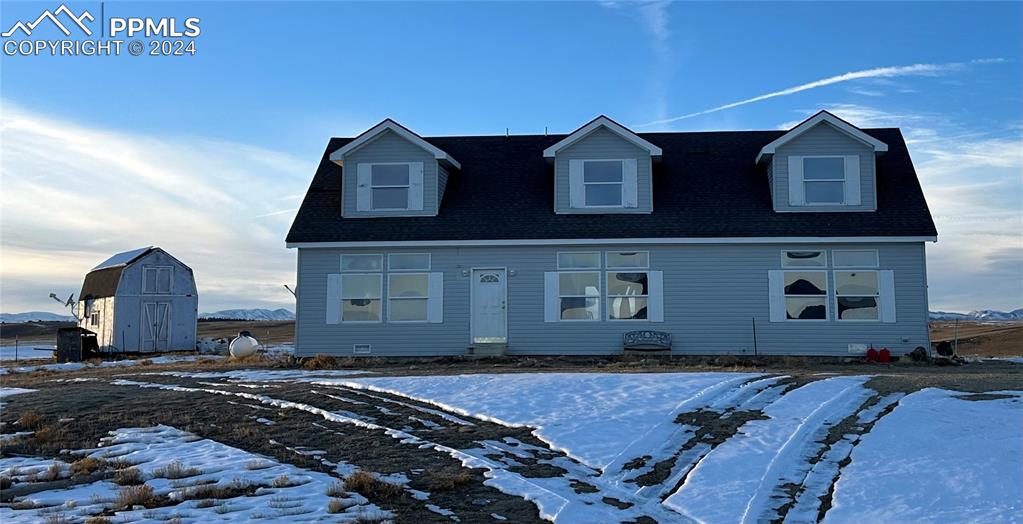 Cape cod house featuring a storage unit